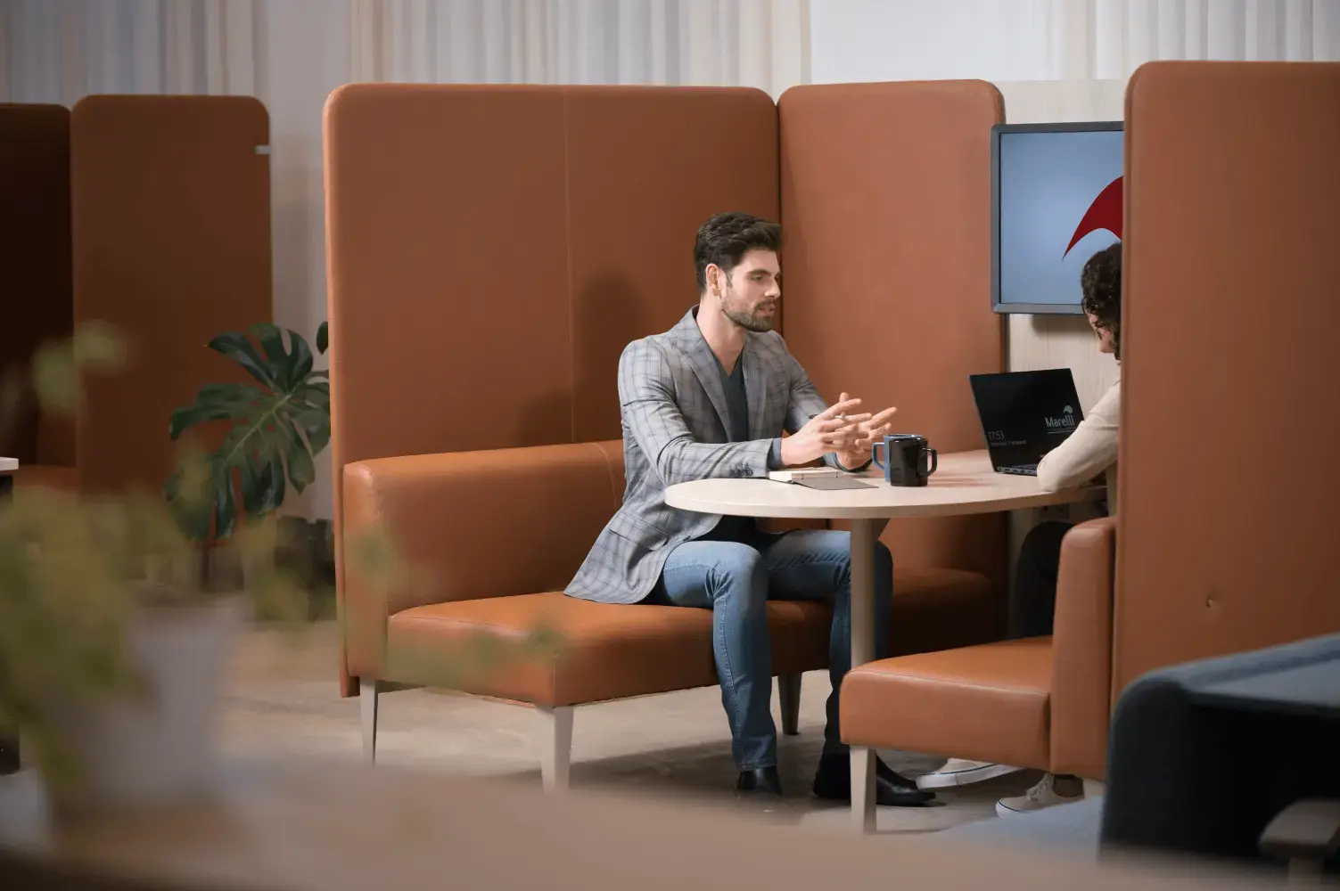 Duas pessoas conversando sentadas a uma mesa em assentos de couro.